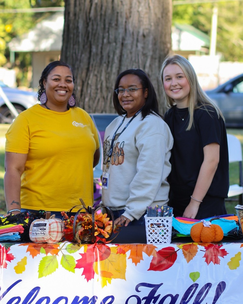 Three ladies standing behind the decorated Martin Housing table