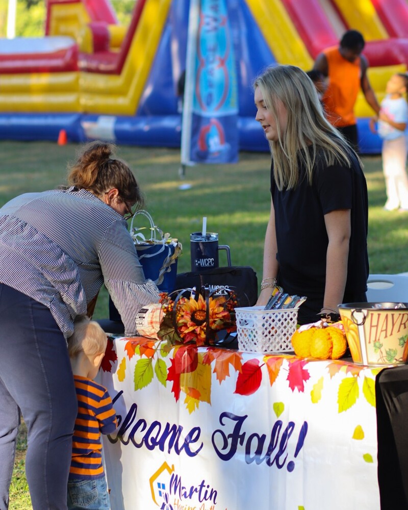 A woman with her child filling out a paper with a lady behind the table.